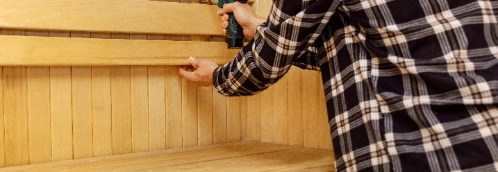 Person baut Sauna mit Akkuschrauber